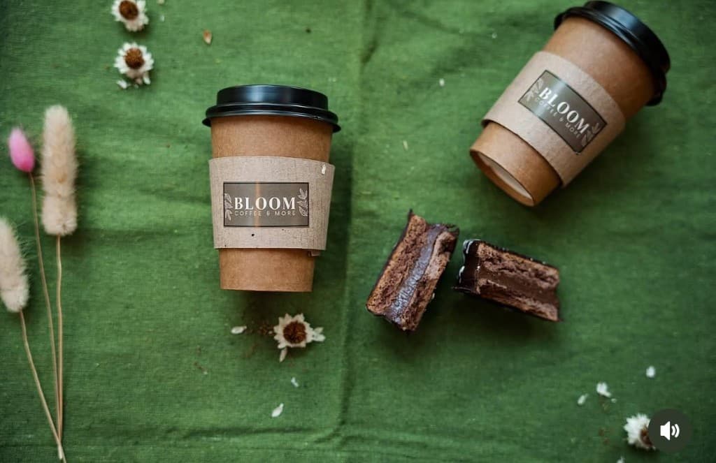 Vasos Bloom Coffee & More y pastelería sobre mantel verde